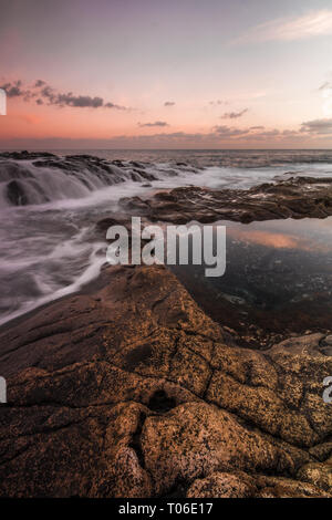 Una lunga esposizione sunrise e colorati di cielo, roccia vulcanica bellissimo paesaggio marino a Gran Canaria Island Costa in Spagna. Foto Stock