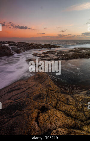 Una lunga esposizione sunrise e colorati di cielo, roccia vulcanica bellissimo paesaggio marino a Gran Canaria Island Costa in Spagna. Foto Stock