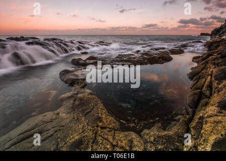 Una lunga esposizione sunrise e colorati di cielo, roccia vulcanica bellissimo paesaggio marino a Gran Canaria Island Costa in Spagna. Foto Stock