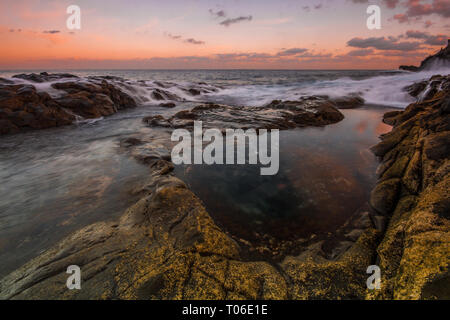 Una lunga esposizione sunrise e colorati di cielo, roccia vulcanica bellissimo paesaggio marino a Gran Canaria Island Costa in Spagna. Foto Stock