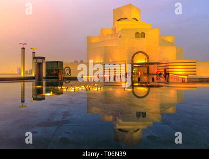 Doha, Qatar - 16 Febbraio 2019: il Museo di Arte Islamica, popolare attrazione turistica, lungo la Corniche riflettendo sulla fontana acqua a cielo al crepuscolo Foto Stock