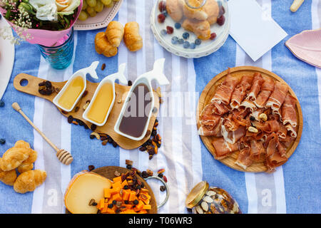 Set di tre sauceboats bianco con il dolce miele sul vassoio in legno a picnic food lay out dello sfondo. Foto Stock