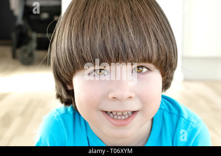 Piccolo ragazzo con capelli lunghi è sempre sorridente e guardando alla fotocamera Foto Stock