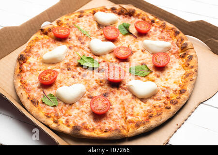 Una gustosa pizza in pizza consegna o scatola di cartone su sfondo bianco. Primo piano Foto Stock