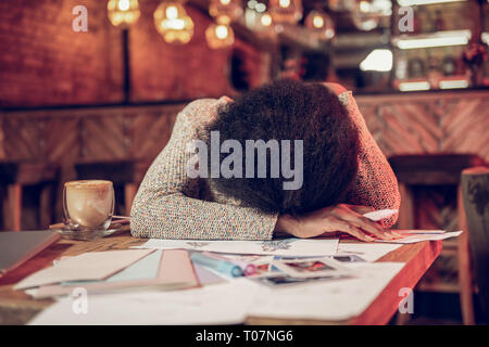 Deluso afro-americane donna appoggiata sul tavolo del bar con schizzi di moda Foto Stock