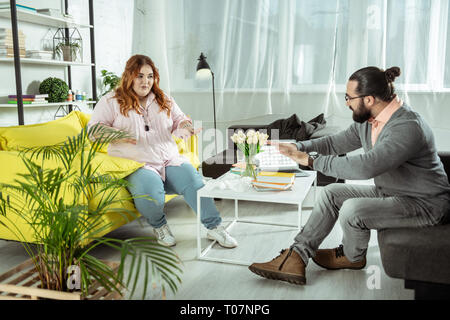 Concentrato di giovane donna grassoccio facendo esercizi di respirazione Foto Stock