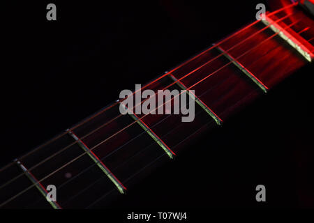 Chitarra elettrica collo illuminato con luce rossa in uno sfondo scuro (foto è liscia e non disturbato come sembra in anteprima) Foto Stock