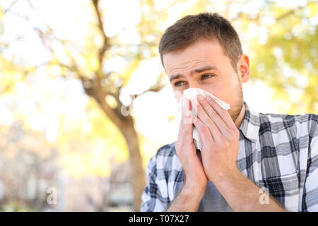 Ill o allergiche uomo tosse nella stagione primaverile in un parco Foto Stock