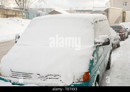 Verde auto è coperto di neve parcheggiato nei pressi della strada Foto Stock