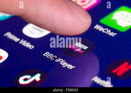 Dito premuto BBC iPlayer icona app su un touchscreen su un tablet PC o telefono mobile device. Caricamento di BBC iPlayer applicazione. BBC iPlayer ]collegamento. Foto Stock
