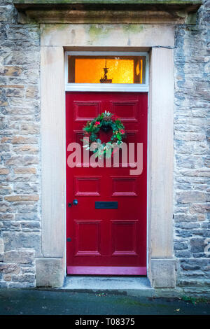 Vecchia casa di pietra con un dipinto di rosso stile Georgiano porta anteriore e una ghirlanda di Natale appeso su di esso Foto Stock