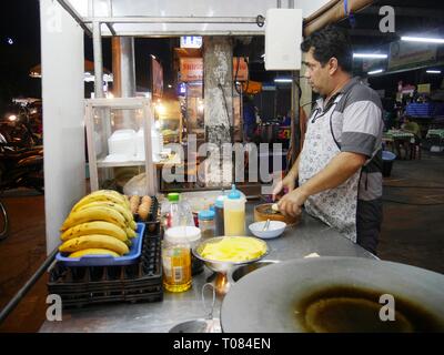 CHIANG mai, THAILANDIA—MARZO 2018: Un uomo affetta una banana per una prelibatezza tailandese in vendita al mercato notturno di Chiang mai. Foto Stock