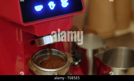 Una macchina elettrica per caffè macinacaffè macina caffè tostato fagioli in un supporto filtro Foto Stock