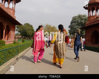 AGRA, UTTTAR PRADESH, INDIA--MARZO 2018: Le donne in abbigliamento tradizionale indiano camminano intorno ai giardini della moschea al Taj Mahal.