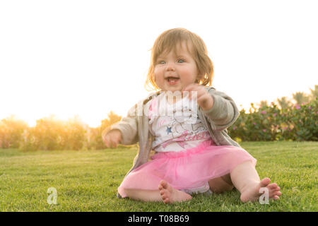 Divertenti felice sorridente ragazza seduta sull'erba Foto Stock