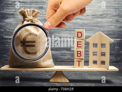 Sacco di denaro e di blocchi di legno con la parola del debito e una casa in miniatura sulle scale. Il pagamento del debito per immobili. Pagare il mutuo ipotecario. Rischi Foto Stock