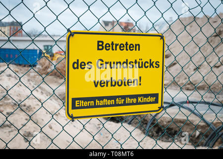 Betreten des Grundstücks verboten ! Eltern haften für ihre Kinder ! Gelbes Schild un Zaun von Baustelle. Foto Stock