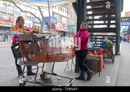 In una fredda giornata invernale, due donne vendere fresco di mais alla griglia e carne alla griglia. Su 82st in Jackson Heights, Queens, NYC sotto il #7 treno scalinata. Foto Stock