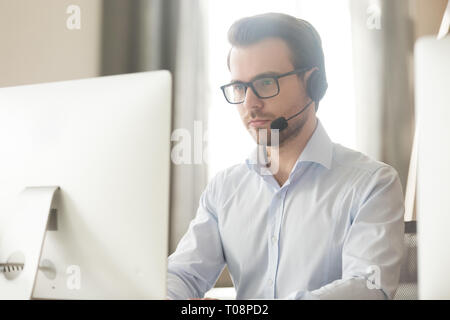 Imprenditore serio parlando con cuffia sul computer che effettua una chiamata in conferenza Foto Stock