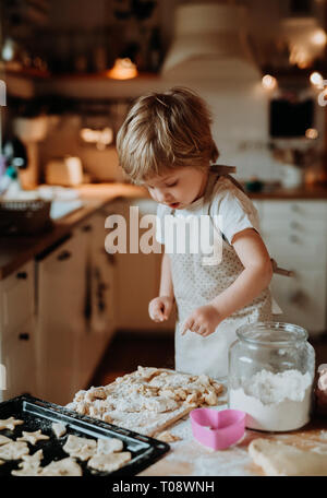 Un felice piccolo bimbo boy fare torte a casa. Foto Stock