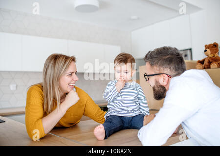 Un Ritratto di giovane famiglia con un bimbo piccolo ragazza in movimento nella nuova casa. Foto Stock