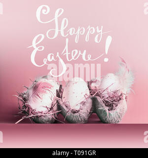 Felice Pasqua biglietto di auguri con uova in griglia con le piume in rosa pastello di sfondo e scritte Foto Stock