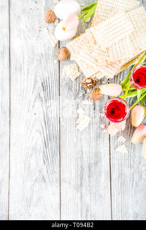 Pesah celebrazione concetto. Pasqua ebraica holiday sfondo con matzo, uova, fiori di primavera, il vino, sfondo verde spazio copia vista superiore Foto Stock