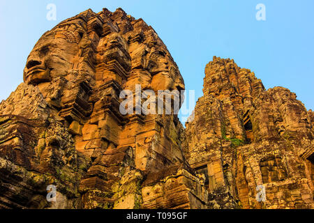 Torri con 2 dei 216 sorridenti facce di pietra arenaria a 12thC tempio Bayon in Angkor Thom città murata; Angkor, Siem Reap, Cambogia. Foto Stock