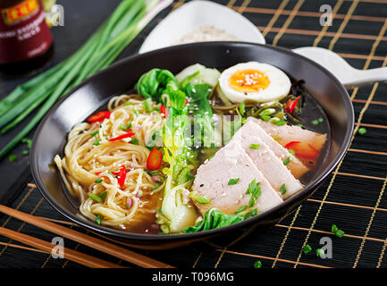 Miso Ramen Asian Tagliatelle con uova, carne di maiale e di pak choi cavolo in ciotola su sfondo scuro. La cucina giapponese. Foto Stock
