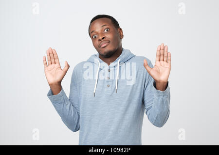 Confuso uomo africano sollevando le palme in surrender, scrollare e rendendo clueless expression Foto Stock