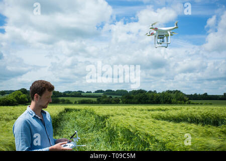 Gran Bretagna, Inghilterra, Wiltshire. L'uomo operando un drone in un crop circle. Foto Stock