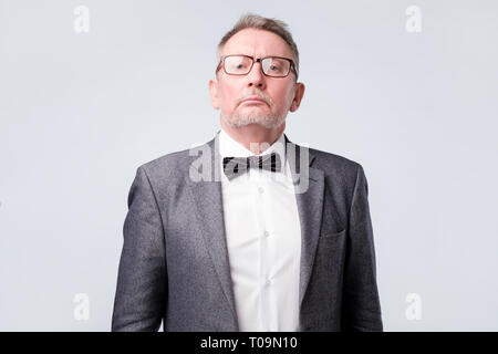 Senior uomo indossare tuta e occhiali alla ricerca seria e fiducioso in telecamera Foto Stock