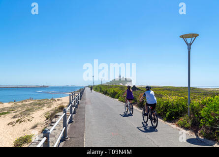 Newcastle, Australia. I ciclisti sul percorso di testa Nobbys e Nobbys Capo Faro, Nobbys Beach, Newcastle, Nuovo Galles del Sud, Australia Foto Stock