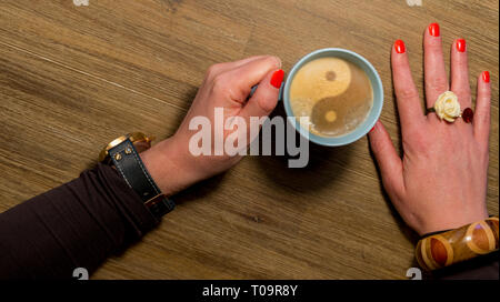 Womans mano azienda tazza di caffè con yin yang segno Foto Stock