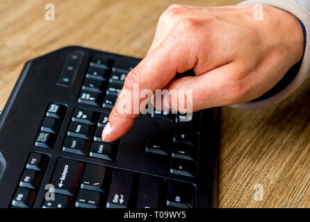 Circa il dito per premere il pulsante Elimina sulla tastiera. Foto Stock