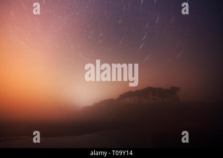 Un cielo notturno, mostrando stelle ruotando attorno alla stella polare, oltre la lontra estuario su una serata di nebbia, Budleigh Salterton, Devon, Gran Bretagna. Foto Stock