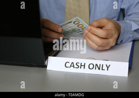 Solo in contanti iscrizione in ufficio, Uomo in camicia blu e cravatta holding di dollari nelle mani di. Cancelliere, un funzionario o un imprenditore prende il denaro per corrompere Foto Stock