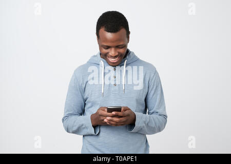African giovane utilizzando il telefono cellulare chat in Internet con i suoi amici. Foto Stock