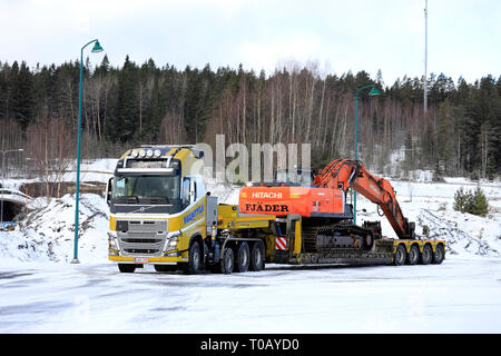 Salo, Finlandia - 9 Marzo 2019: Giallo Volvo FH16 Mantyla su un cantiere pronto per il traino di un carico ingombrante di Hitachi ZX 350LC escavatore cingolato in un giorno d'inverno. Foto Stock
