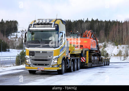 Salo, Finlandia - 9 Marzo 2019: Volvo FH16 Mantyla autocarro con rimorchio a pianale ribassato che trasportano Hitachi ZX 350LC escavatore ampia carico su un giorno d'inverno. Foto Stock