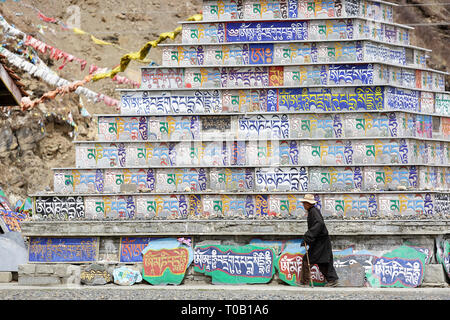 Pellegrini a mani lungo muro di pietra, Tagong, Sichuan, in Cina Foto Stock