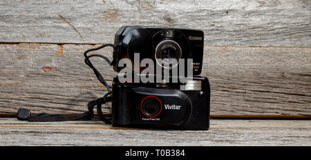 Vecchio fotocamere point and shoot impilata su ogni altra contro uno sfondo di legno. Foto Stock