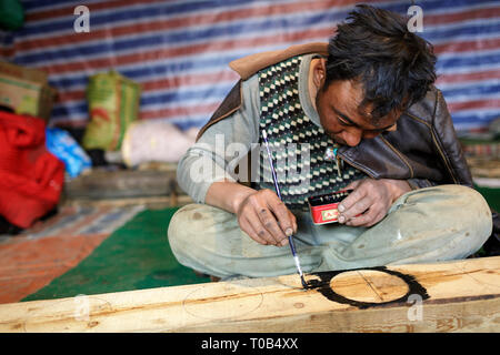 Il Tibetano uomo pittura tavola di legno con schemi tradizionali Foto Stock