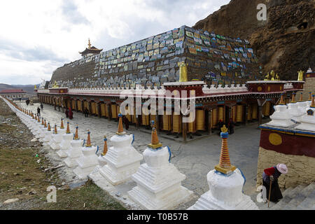 Pellegrini a mani lungo muro di pietra a Ser Gergyo (Ani Gompa) convento, Tagong, Sichuan, in Cina Foto Stock