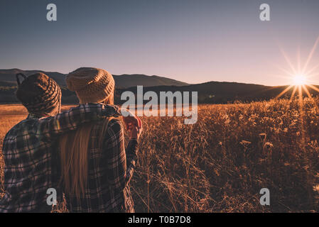 Un giovane si trova in un campo e si ammira il tramonto in Cades Cove, Great Smoky Mountains National Park. Foto Stock