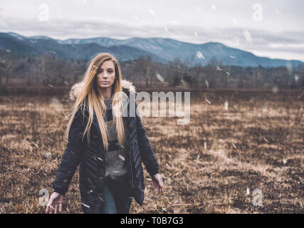 Una giovane donna cammina attraverso Cades Cove nel Parco Nazionale di Great Smoky Mountains all'inizio di una tempesta di neve che è persistito fino al giorno successivo. Foto Stock