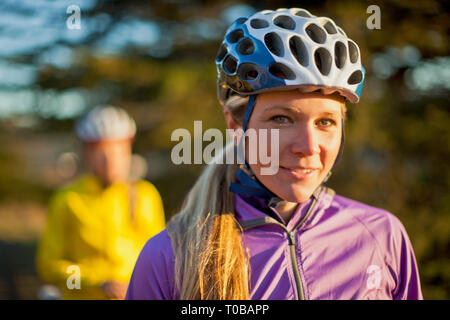 Ritratto di un sorridente giovane donna che indossa un casco in bicicletta. Foto Stock