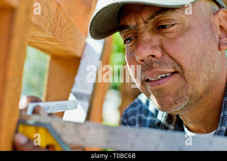 Builder utilizzando un martello su un sito in costruzione. Foto Stock