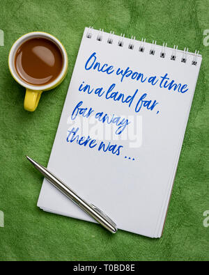 Una volta in una terra lontana - una frase di apertura di narrazioni orali, storia o favola scritta a mano in un'arte sketchbook con una tazza di caffè Foto Stock