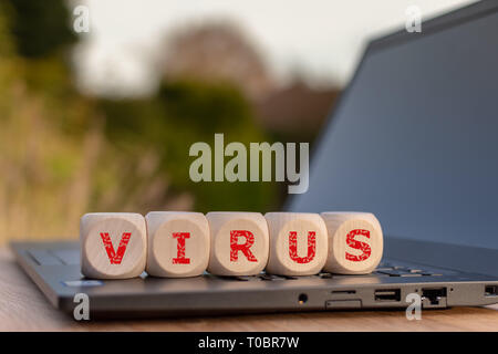 Dadi collocato su un notebook forma la parola "VIRUS". Foto Stock